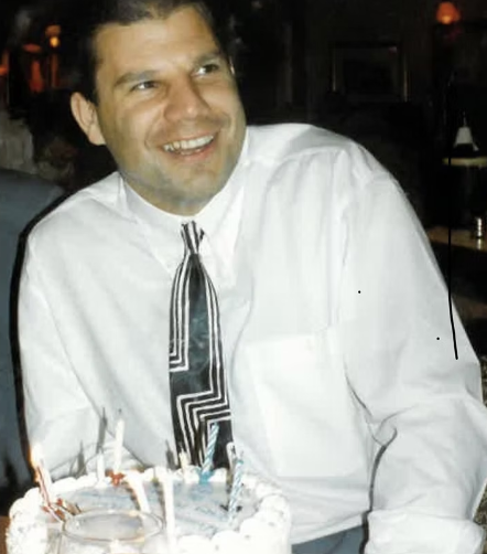 Michael "Mitchy" Badnall, smiling behind a birthday cake.